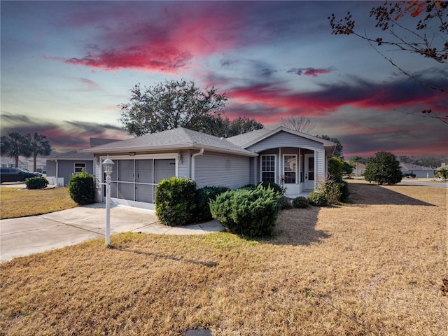 ranch-style house with a garage, concrete driveway, and a front lawn