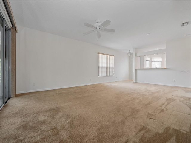 carpeted empty room featuring a ceiling fan, visible vents, and baseboards