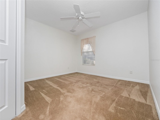 carpeted spare room featuring a ceiling fan, visible vents, a textured ceiling, and baseboards