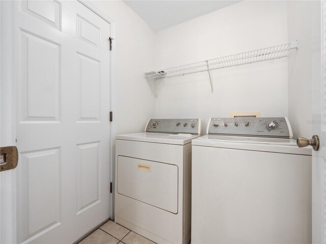 clothes washing area with laundry area, washer and clothes dryer, and light tile patterned floors