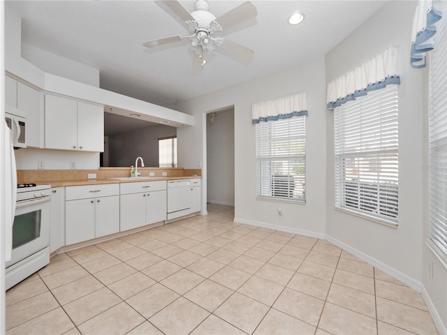 kitchen with white appliances, light countertops, a sink, and baseboards