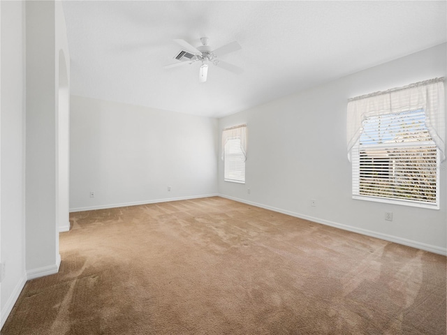 empty room featuring visible vents, baseboards, a ceiling fan, and light colored carpet