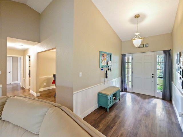 entrance foyer with high vaulted ceiling, a wainscoted wall, and dark wood-type flooring