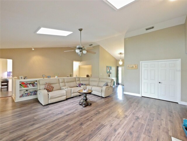 living room with ceiling fan, hardwood / wood-style flooring, a skylight, and high vaulted ceiling