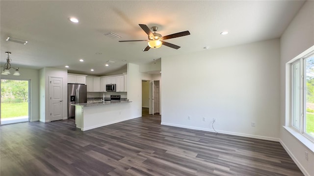 kitchen featuring white cabinetry, decorative light fixtures, light stone countertops, appliances with stainless steel finishes, and dark wood-type flooring