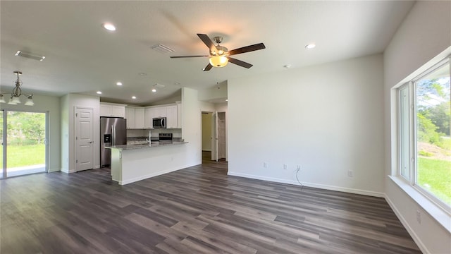 kitchen with white cabinetry, stainless steel appliances, ceiling fan with notable chandelier, light stone counters, and dark hardwood / wood-style floors