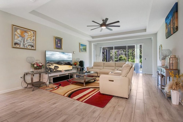 living room featuring a tray ceiling, light hardwood / wood-style flooring, and ceiling fan