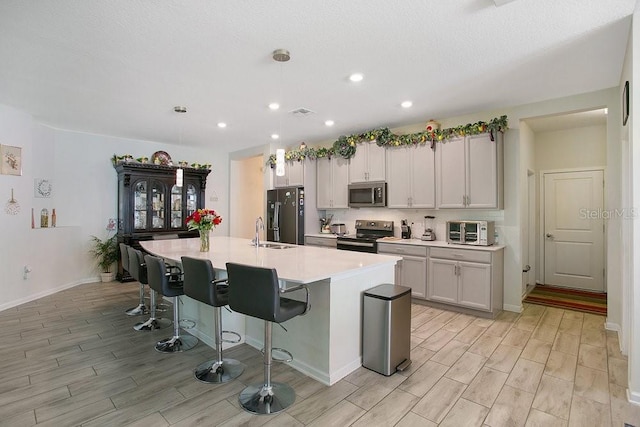 kitchen with white cabinetry, a breakfast bar, an island with sink, and appliances with stainless steel finishes