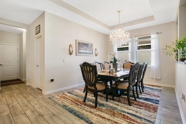 dining area with a raised ceiling and an inviting chandelier