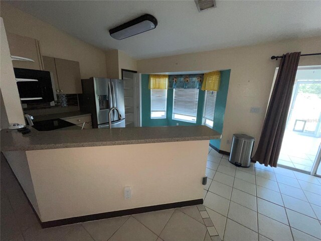 kitchen featuring stainless steel fridge, sink, light tile patterned floors, and kitchen peninsula