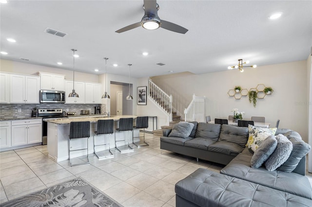 living room with sink, light tile patterned flooring, and ceiling fan with notable chandelier