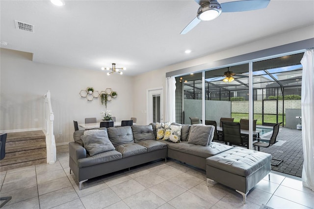 tiled living room featuring ceiling fan with notable chandelier