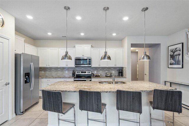 kitchen featuring light tile patterned floors, appliances with stainless steel finishes, decorative backsplash, and decorative light fixtures