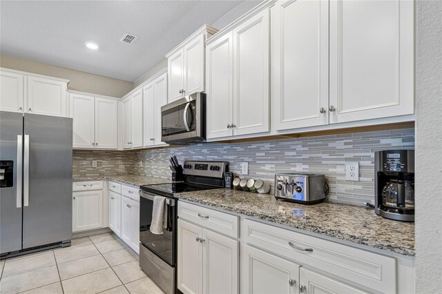 kitchen with appliances with stainless steel finishes, decorative backsplash, light stone counters, white cabinets, and light tile patterned flooring