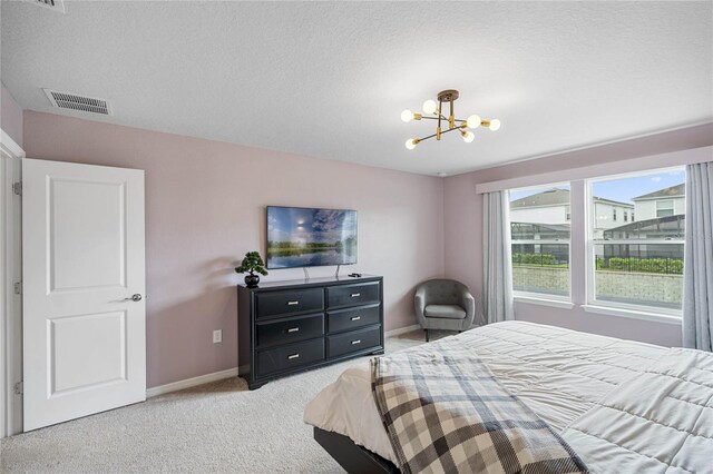 bedroom with a textured ceiling, light carpet, and a chandelier