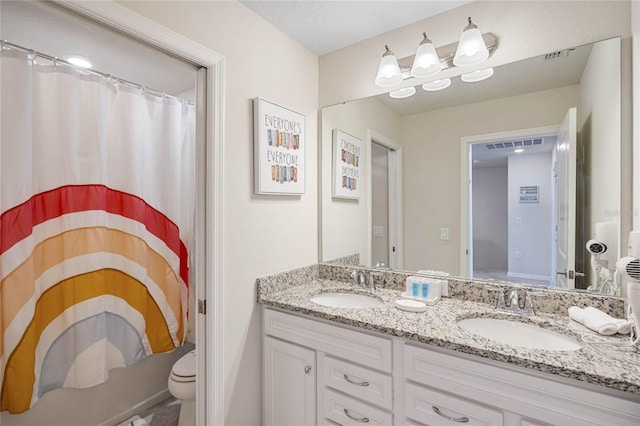 bathroom with toilet and double sink vanity