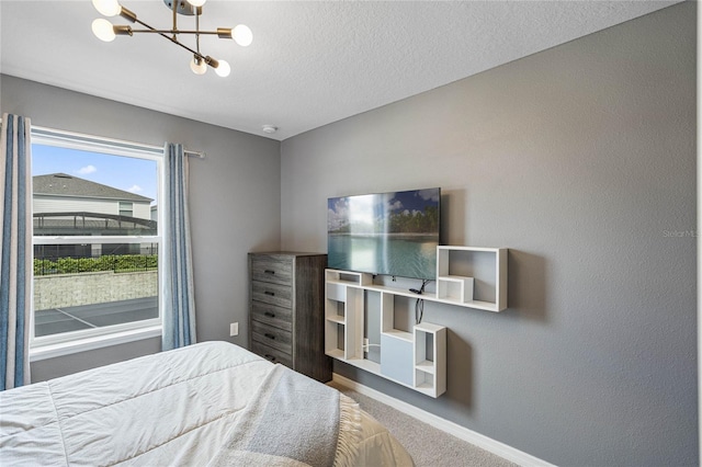 bedroom with a textured ceiling, carpet floors, and a notable chandelier