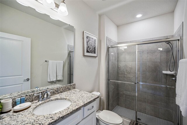 bathroom featuring toilet, vanity, and walk in shower