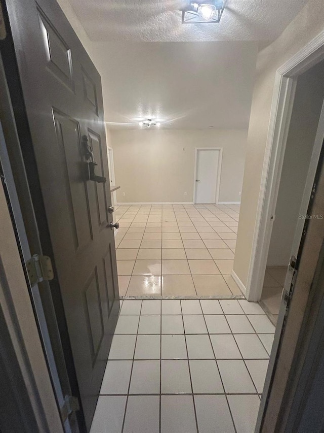 hallway featuring light tile patterned flooring and a textured ceiling