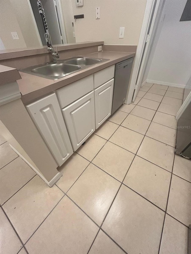 kitchen featuring sink, stainless steel dishwasher, white cabinets, and light tile patterned floors