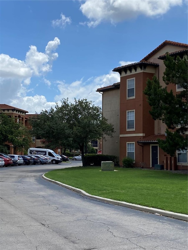 5578 Metrowest Blvd Unit 107, Orlando, FL 32811 - view of side of home with a tiled roof, uncovered parking, a yard, and stucco siding