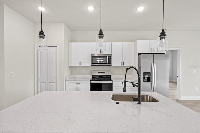 kitchen featuring light stone counters, sink, white cabinetry, appliances with stainless steel finishes, and decorative light fixtures