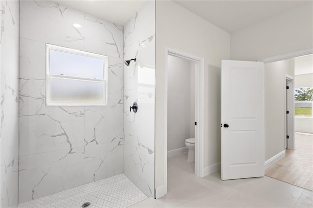 bathroom featuring hardwood / wood-style flooring, toilet, and tiled shower