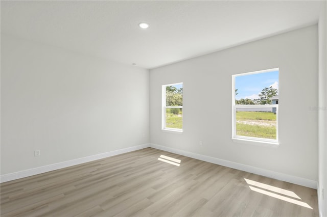 spare room featuring a wealth of natural light and light hardwood / wood-style floors