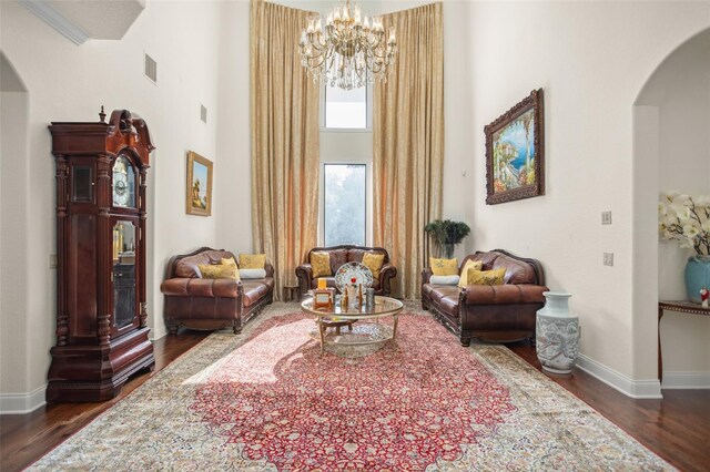 living area with ornamental molding, dark wood-type flooring, and a towering ceiling