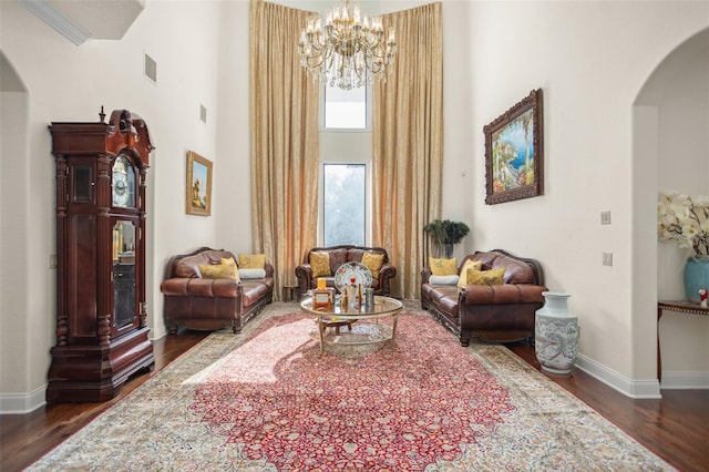 living area featuring a high ceiling, a notable chandelier, and dark hardwood / wood-style flooring