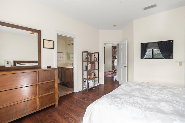 bedroom with connected bathroom and dark wood-type flooring