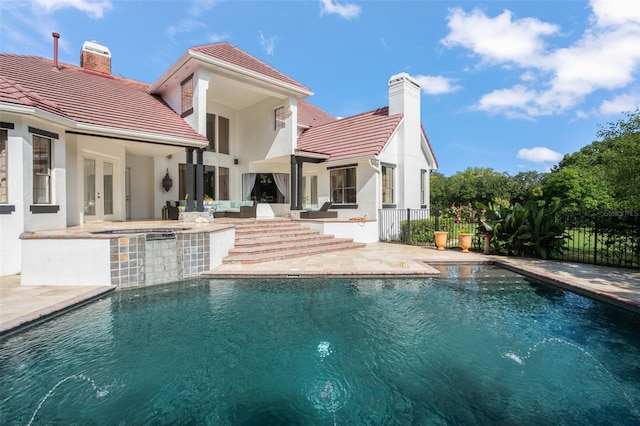 rear view of house featuring a pool with hot tub and a patio