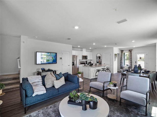 living room featuring recessed lighting, visible vents, dark wood finished floors, and stairs