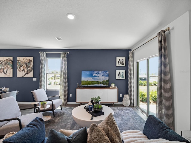 living room featuring a healthy amount of sunlight, visible vents, baseboards, and wood finished floors