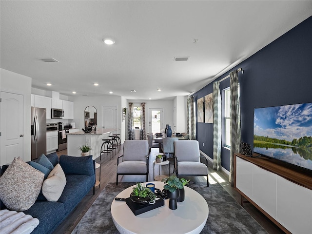 living room with recessed lighting, visible vents, and dark wood finished floors