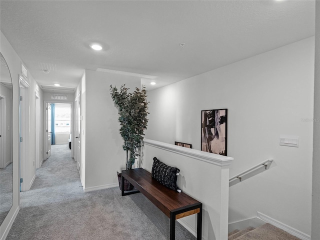 hallway featuring a textured ceiling, recessed lighting, light colored carpet, an upstairs landing, and baseboards