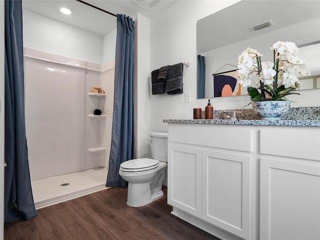 full bathroom featuring visible vents, toilet, a stall shower, vanity, and wood finished floors