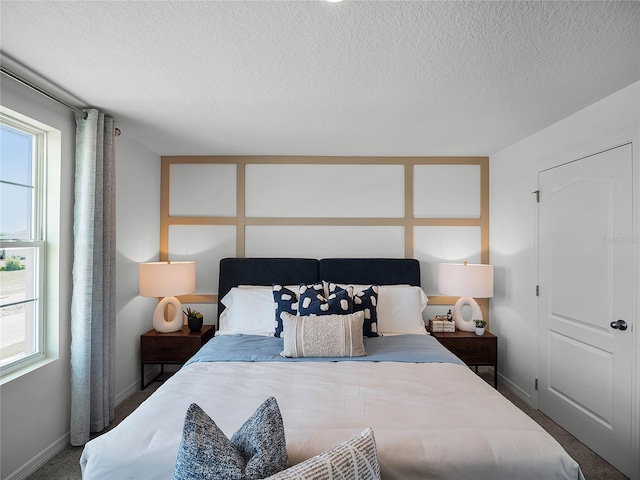 bedroom featuring carpet, multiple windows, baseboards, and a textured ceiling