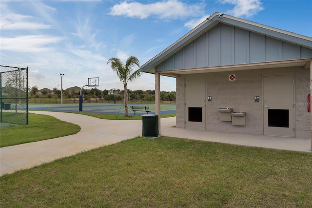 view of home's community with a yard, community basketball court, and fence