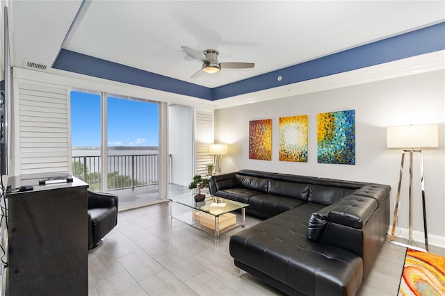 living room with ceiling fan and a raised ceiling