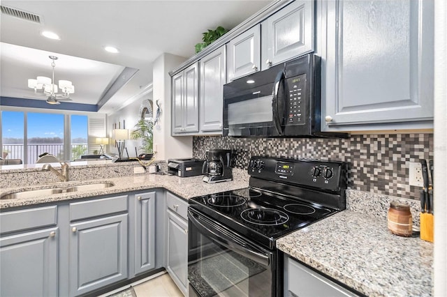 kitchen with tasteful backsplash, gray cabinets, light stone counters, black appliances, and sink