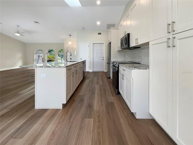 kitchen featuring light stone countertops, an island with sink, appliances with stainless steel finishes, and white cabinets