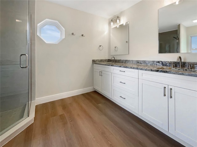 bathroom with hardwood / wood-style floors, an enclosed shower, and dual bowl vanity