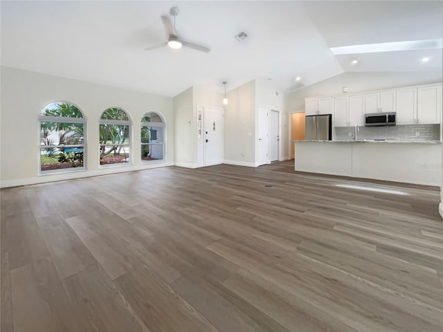 unfurnished living room featuring dark hardwood / wood-style floors, lofted ceiling, sink, and ceiling fan