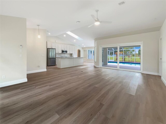 unfurnished living room featuring vaulted ceiling, hardwood / wood-style floors, and ceiling fan