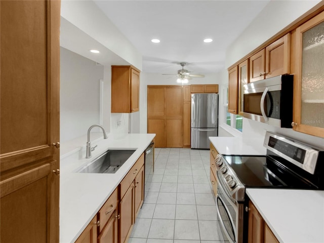 kitchen with light tile patterned floors, appliances with stainless steel finishes, sink, and ceiling fan