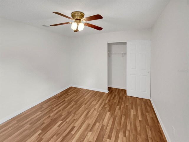 unfurnished bedroom with light wood-type flooring, ceiling fan, and a closet