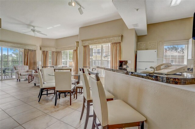 interior space with ceiling fan, rail lighting, white fridge, and light tile patterned floors