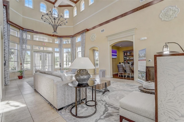 living room featuring a notable chandelier, light tile patterned flooring, a towering ceiling, and french doors