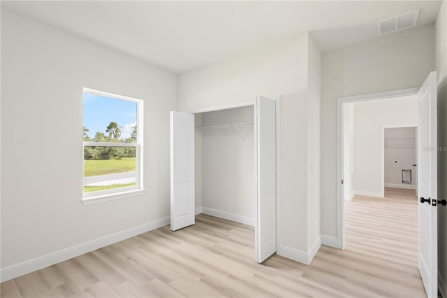 unfurnished bedroom with light wood-type flooring and a closet